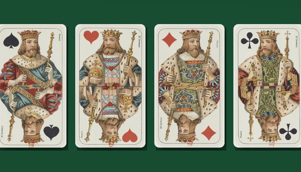 The kings of spades, hearts, diamonds and clubs from a 19th-century Grimaud deck laid side by side on green felt